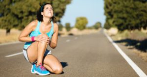 Woman crying for a painful knee injury during running training.